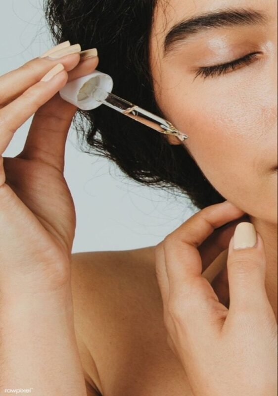 Close-up of woman applying anti-ageing serum with dropper as part of morning or night skincare routine.