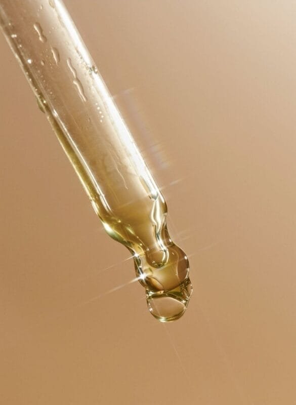 Close-up of a skincare dropper with golden anti-ageing serum, representing hydration and lipid support for skin barrier repair.