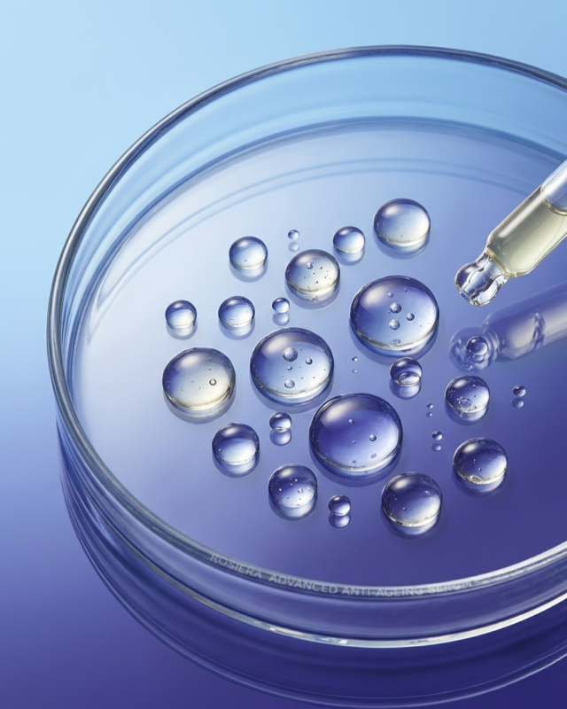 The Climate-Smart Guide: How to Fix Sticky, Dull Skin in Indian Summer and Monsoon Humidity 2 Close up view of fluid, lightweight serum droplets reflecting a premium Blue Lotus brand color background.